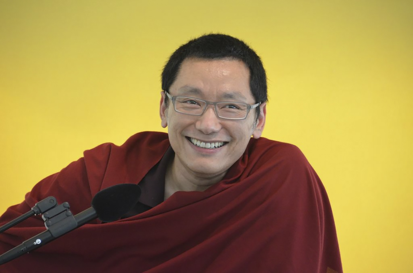 A smiling Buddhist monk with glasses